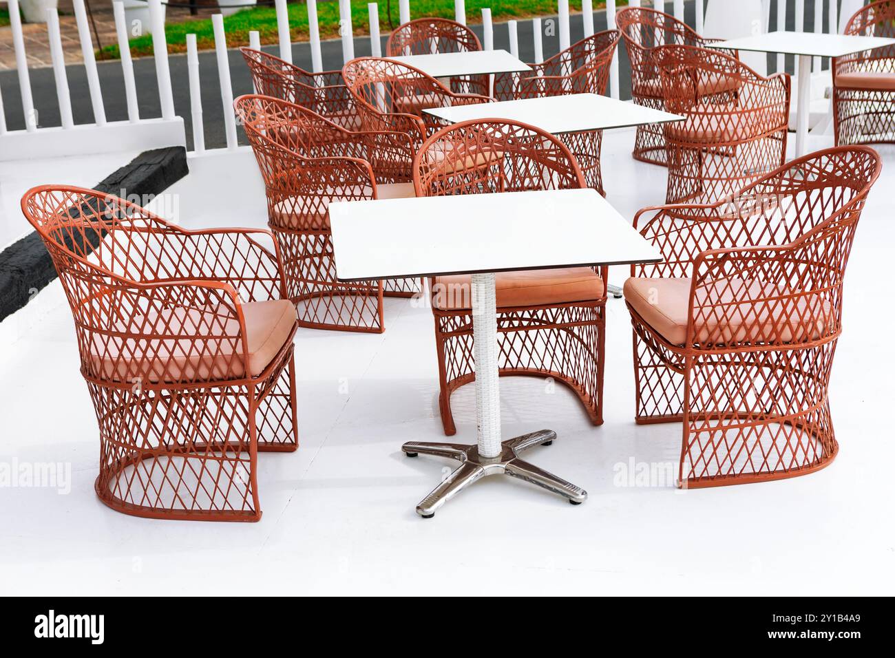 Patio confortable avec des tables en bois entourées de chaises, parfait pour les repas en plein air et la détente Banque D'Images