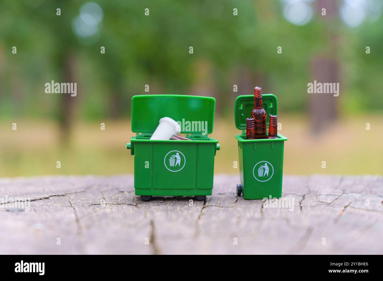 Deux bacs de recyclage verts miniatures remplis de bouteilles en plastique et en verre, illustrant l'importance de séparer les déchets. Banque D'Images