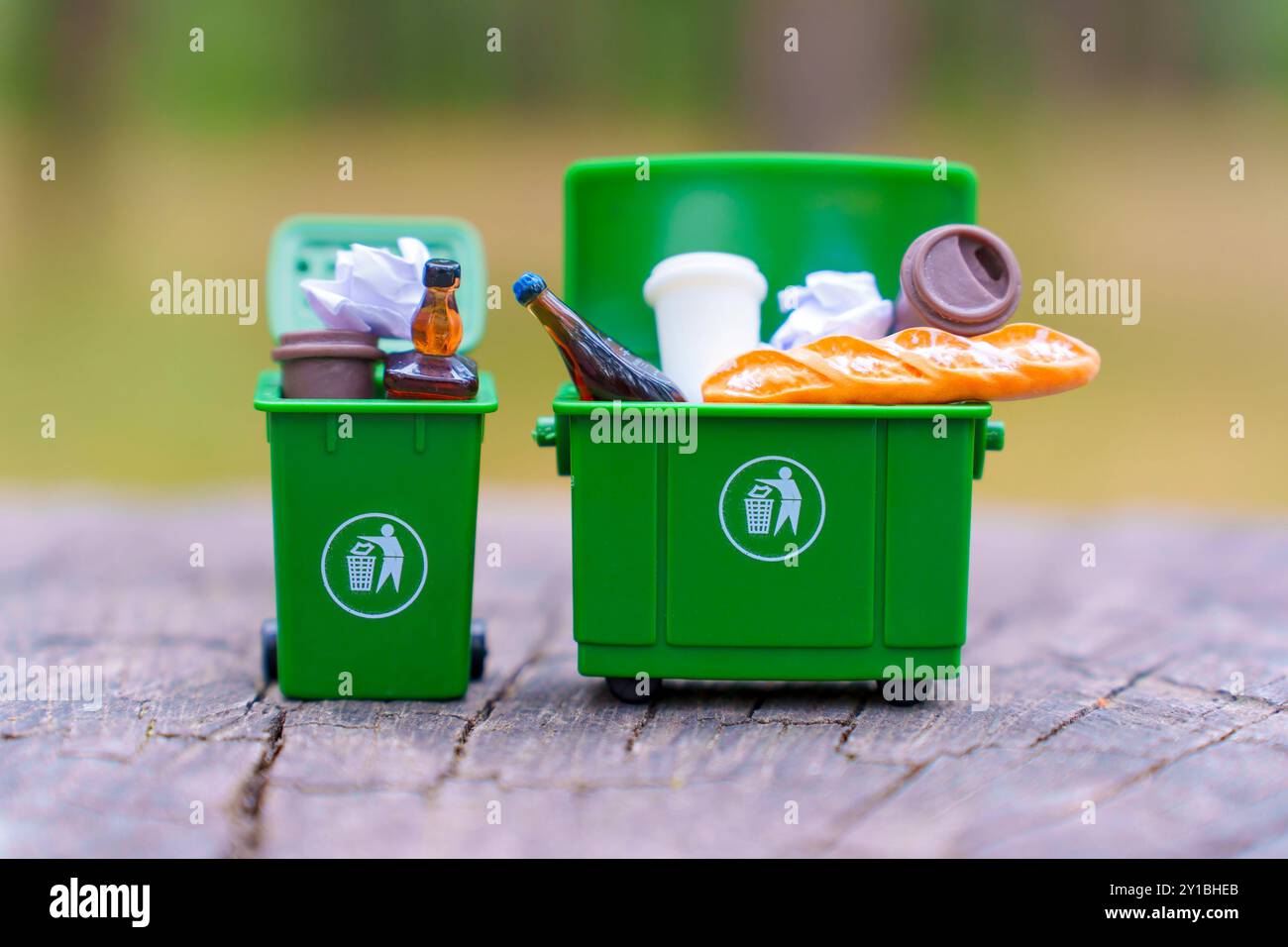 Deux poubelles miniatures vertes remplies de divers déchets, soulignant l'importance de la séparation dans le recyclage des déchets. Banque D'Images