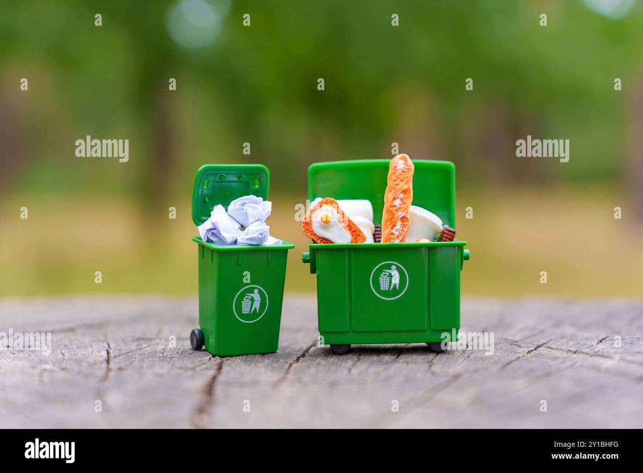 Deux poubelles miniatures vertes remplies de déchets non triés, mettant en évidence les concepts de gestion et de recyclage des déchets. Banque D'Images