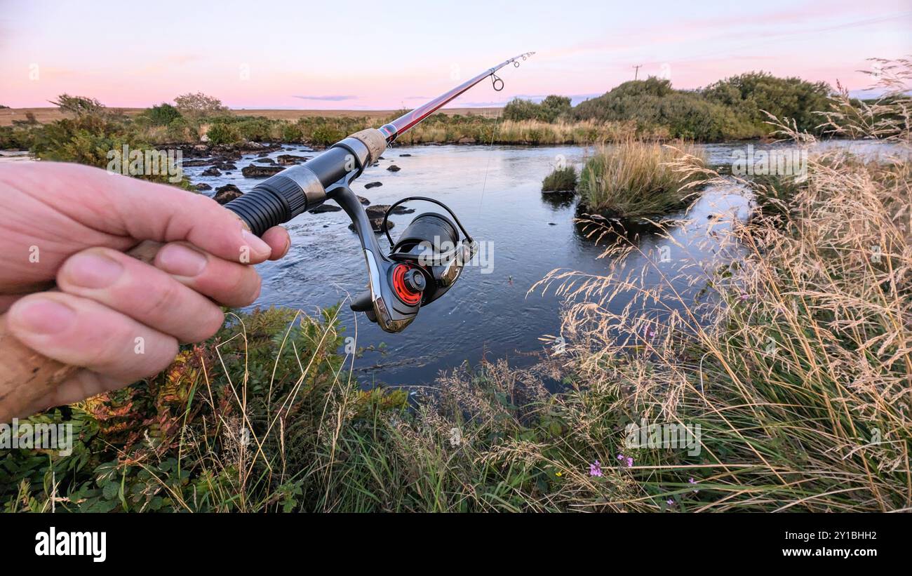 Main tenant une canne à pêche et un moulinet, pêche sur la rivière Corrib à Galway, Irlande, filature, pêche à la ligne, capture et relâchement, sport et loisirs, nature backgro Banque D'Images