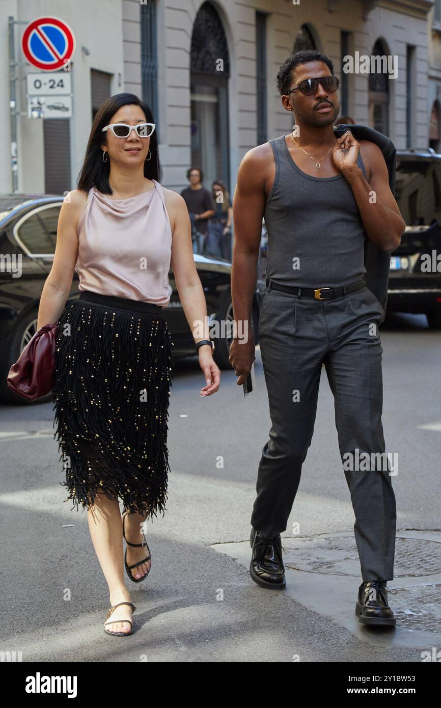 MILAN, ITALIE - 16 JUIN 2024 : femme et homme avec jupe avec perles noires et dorées et maillot gris avant le défilé Dunhill, Milan Fashion week St Banque D'Images