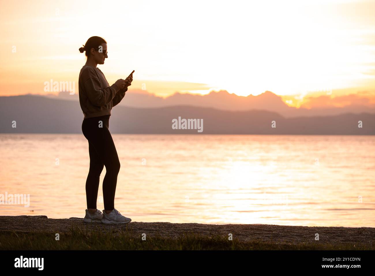 Silhouette d'une femme utilisant la technologie au coucher du soleil près du lac Ohrid Banque D'Images