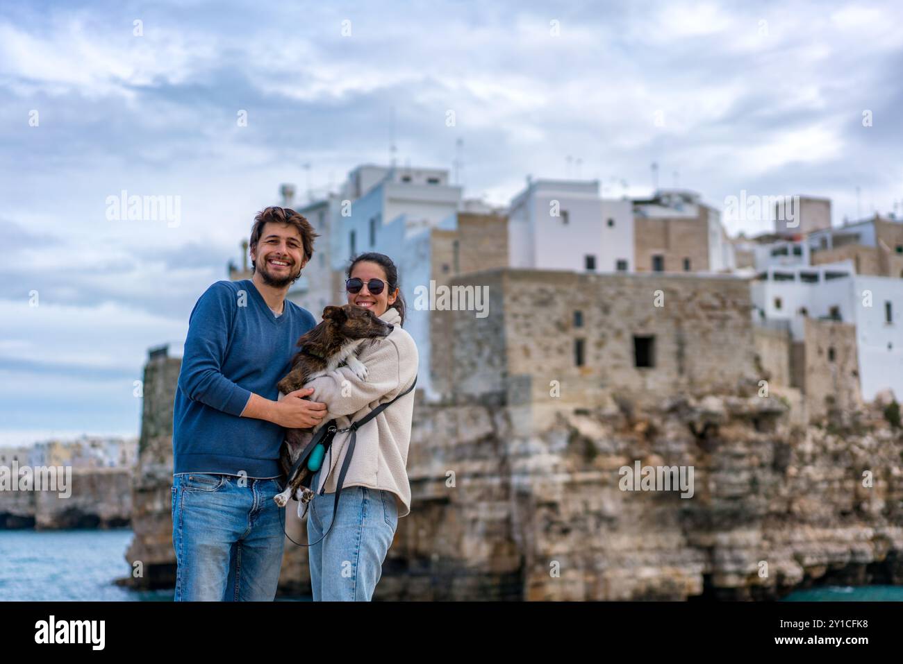 Couple avec chien brun souriant à la caméra à Polignano a Mare Banque D'Images
