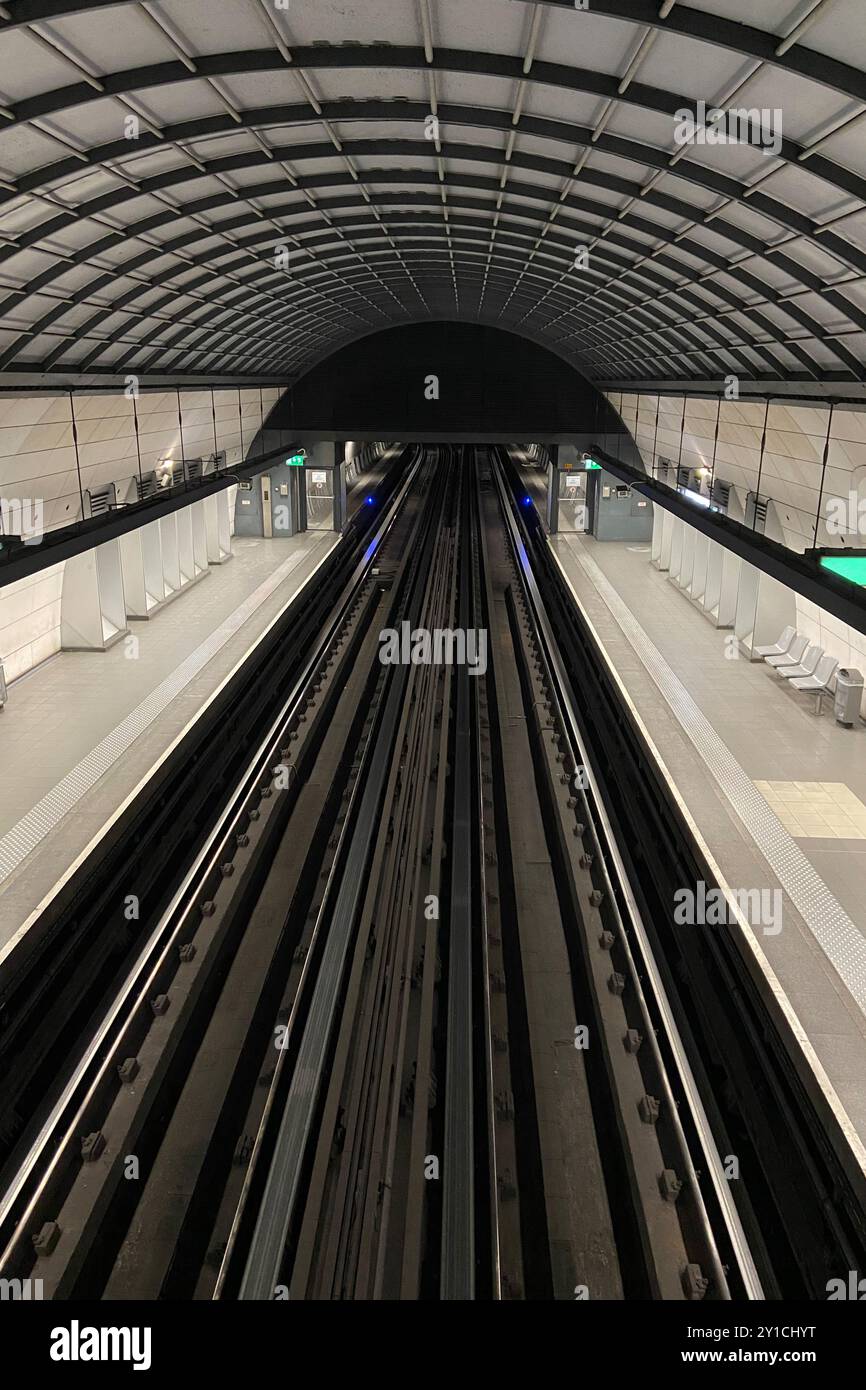 Vue en perspective des quais de train déserts vides et des rails d'une grande station de métro de banlieue urbaine à Lyon, France Banque D'Images