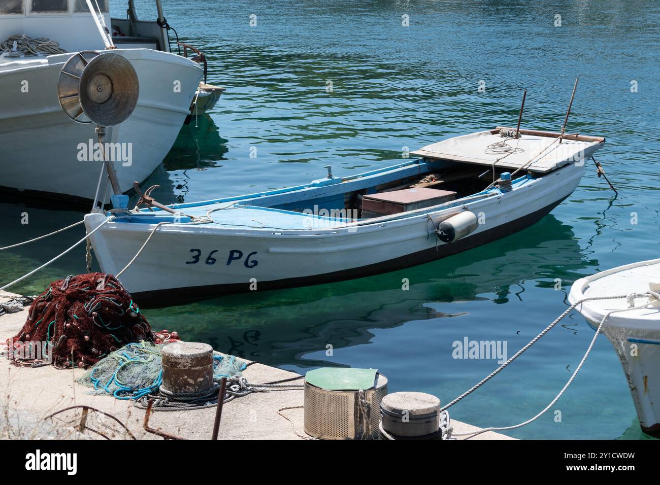 Vieux bateau amarré au quai et pile de filet de pêche à côté du bateau Banque D'Images