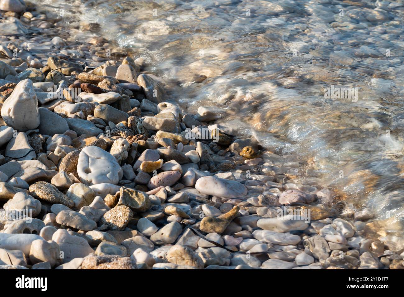 Une petite vague jaillit sur des galets sur la plage Banque D'Images