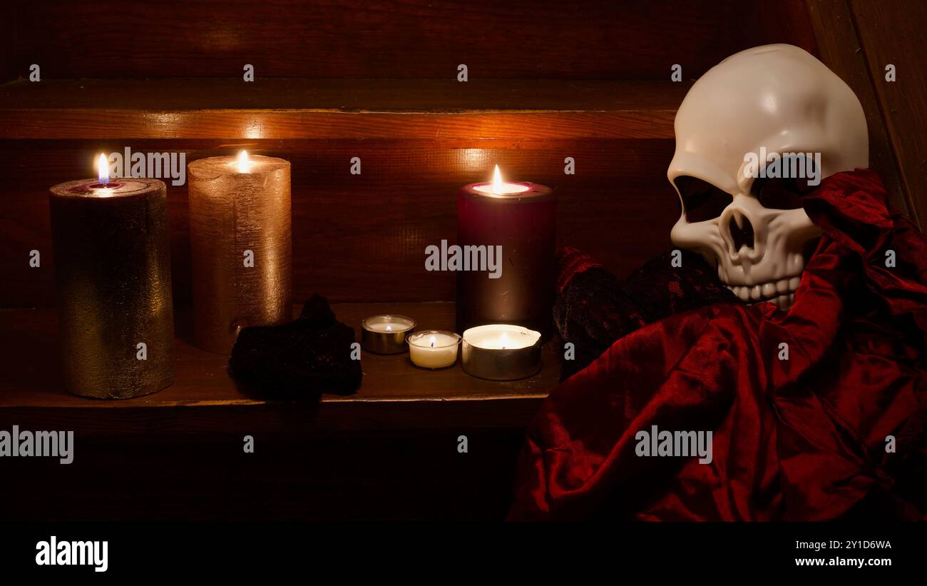Un crâne sur les escaliers, des bougies, une robe rouge. Spooky Halloween concept. Banque D'Images Un crâne sur les escaliers, des bougies, une robe rouge. Spooky Halloween concept. Banque D'Images