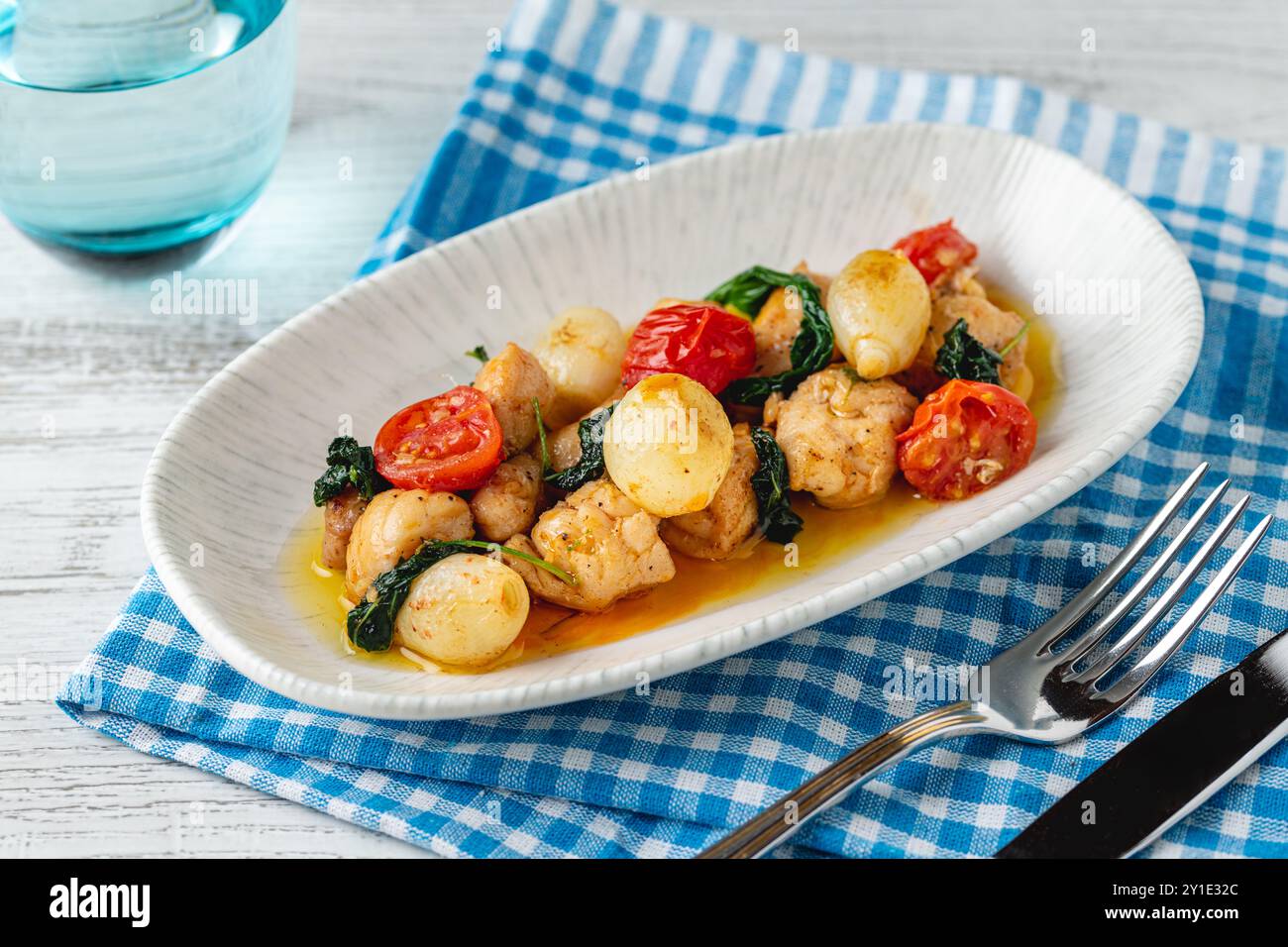 Apéritif avec des crevettes, des oignons et des tomates sur une assiette en porcelaine blanche Banque D'Images