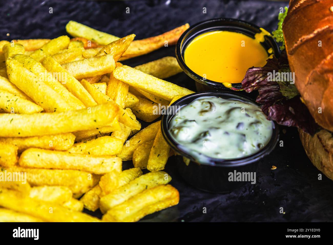 Hamburger avec frites croustillantes, sauce tartare et sauce au fromage cheddar sur le côté Banque D'Images