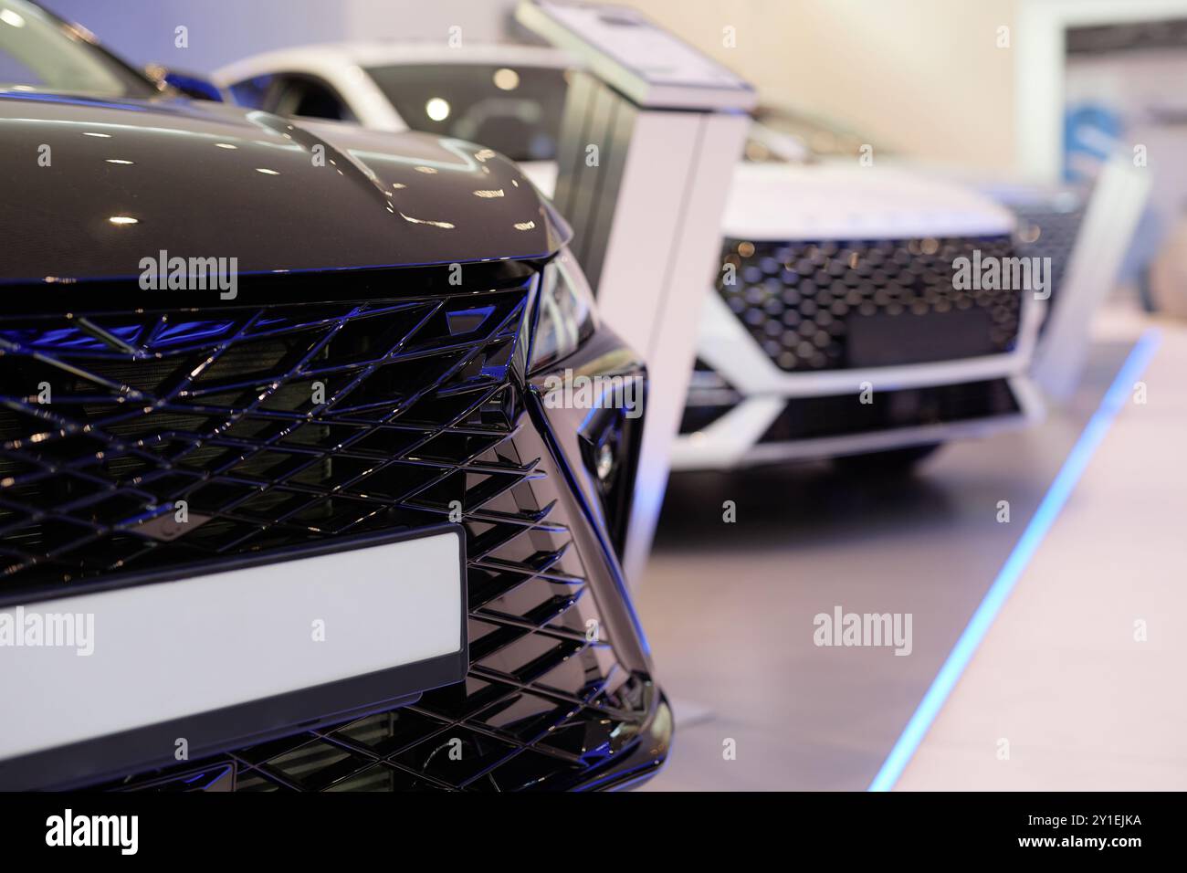 Gros plan sur la calandre noire de la voiture brutale avec une maquette vierge de plaque d'immatriculation affichée dans la salle d'exposition du centre de l'établissement concessionnaire, espace copie Banque D'Images