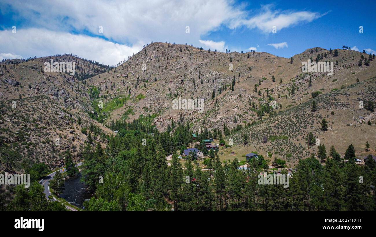 Une vue panoramique d'une route sinueuse traversant une nature sauvage montagneuse, entourée de terrains rocheux et d'arbres denses. Banque D'Images
