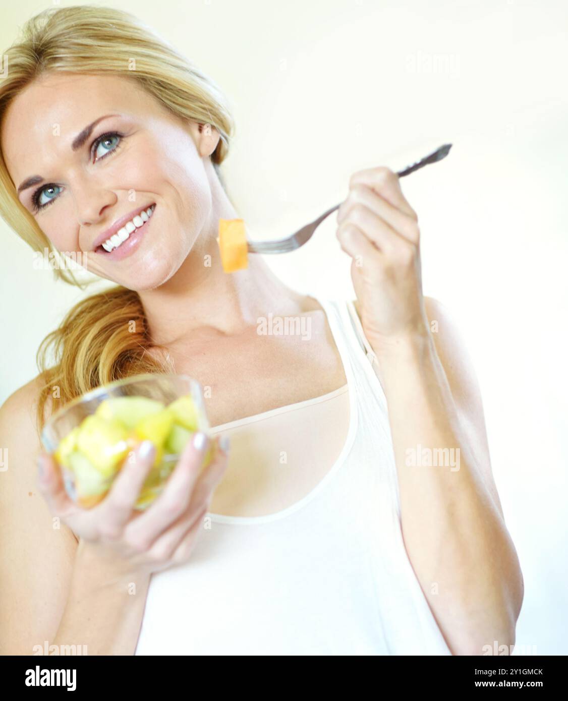Sourire, femme ou idées de salade de fruits en studio avec petit déjeuner sain et minéraux pour les vitamines. Matin, fond blanc et personne pensant à Banque D'Images