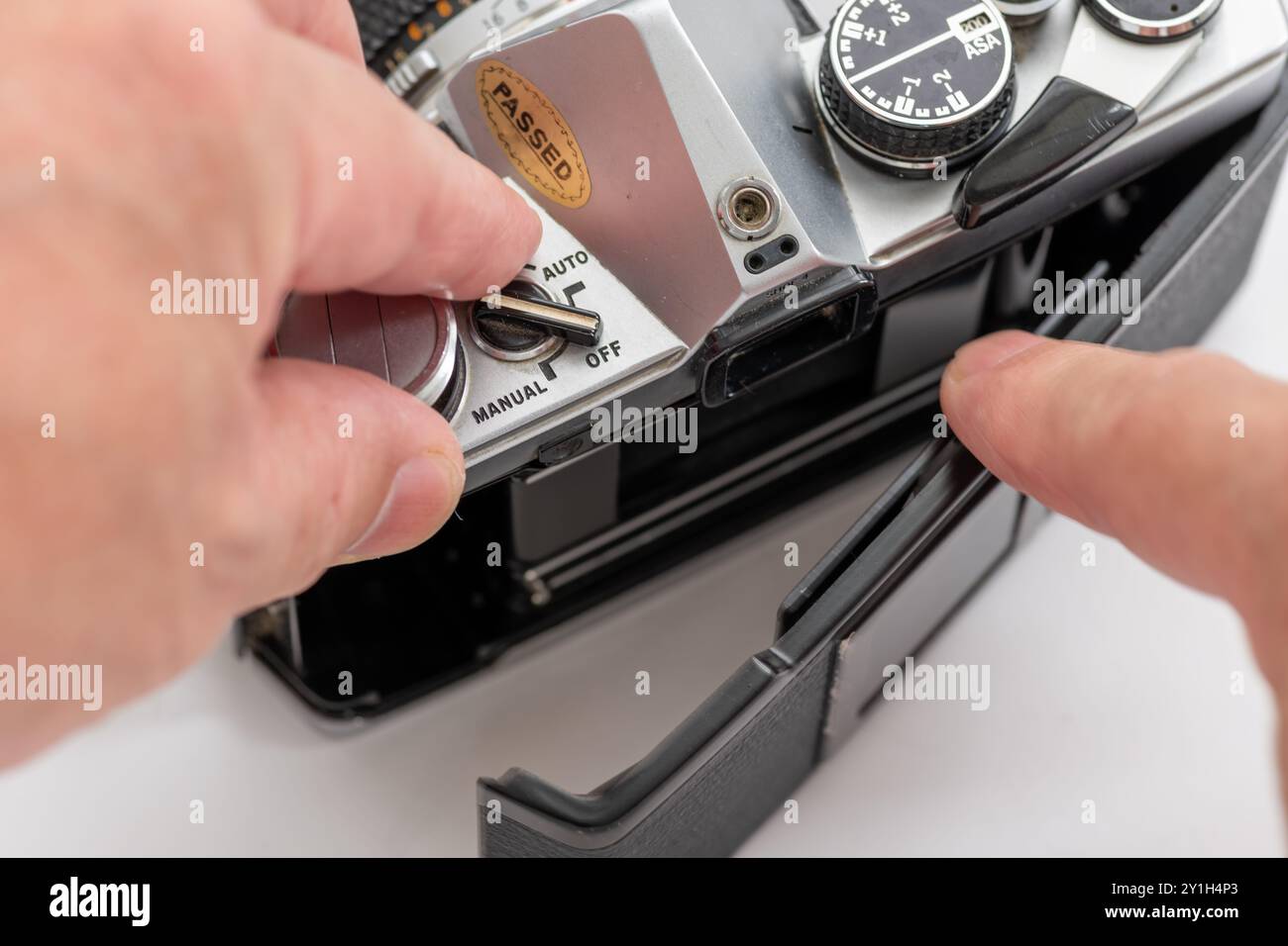 Gros plan d'une personne ouvrant le couvercle arrière pour insérer le rouleau de film dans un appareil photo reflex vintage. Banque D'Images