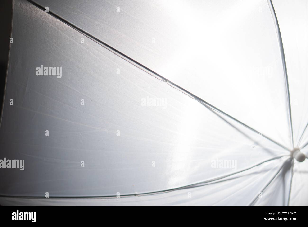 Gros plan d'un parapluie blanc avec la lumière du soleil qui brille à travers, créant un effet de lumière douce et diffuse. Banque D'Images