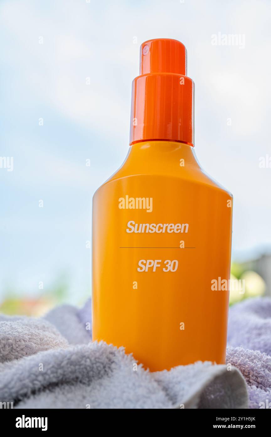 Bouteille de crème solaire jaune debout entre une serviette sur une table, pour la protection uv des personnes. Prévenir pour développer le cancer de la peau. Plan vertical, été Banque D'Images
