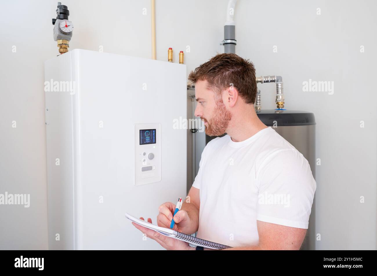 Le technicien vérifie le fonctionnement d'une pompe à chaleur dans une maison. Banque D'Images