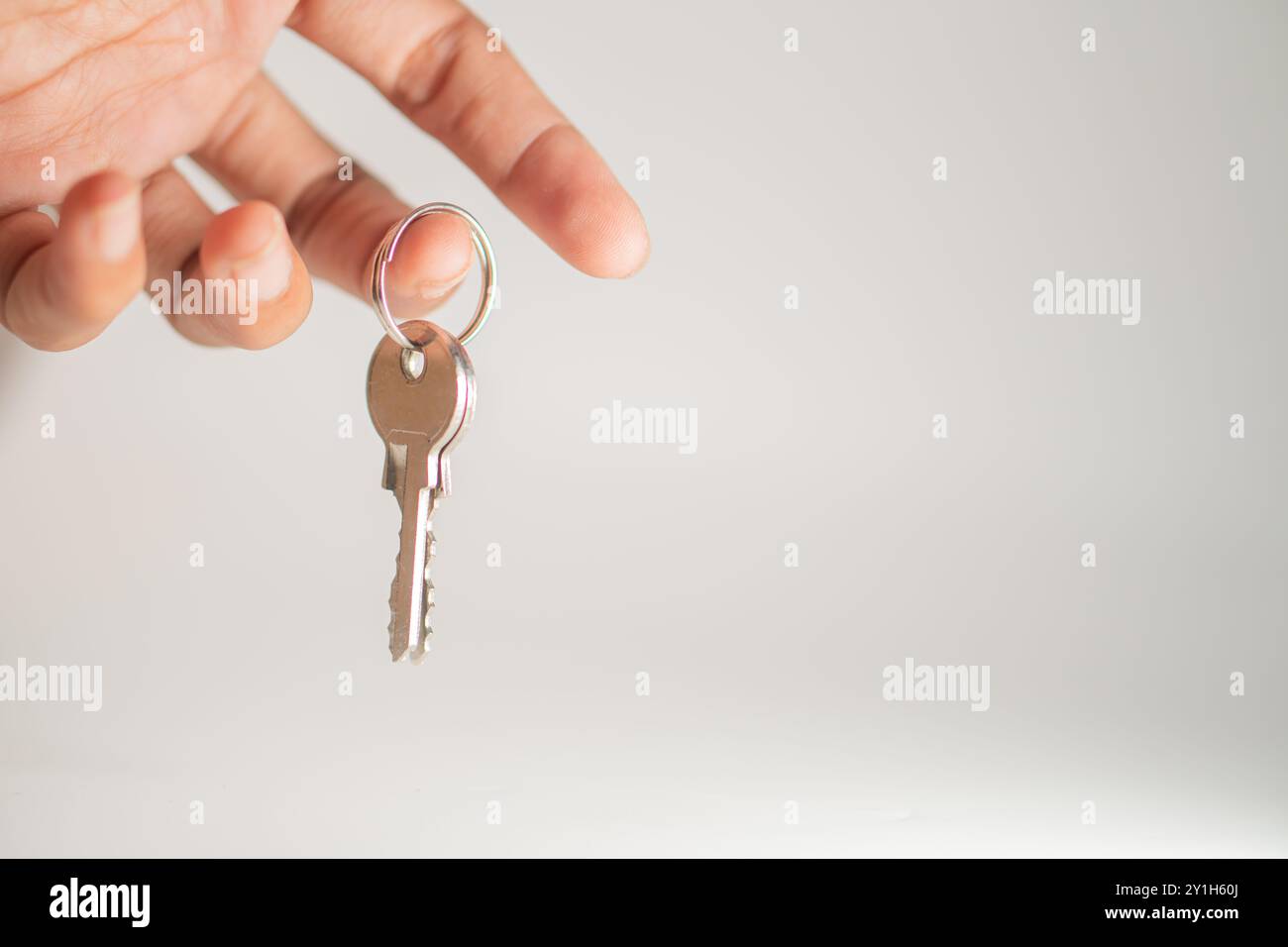 Gros plan d'une main tenant une touche sur un porte-clés, avec un arrière-plan flou. La clé est métallique et brillante, symbolisant la sécurité et l'accès. Banque D'Images