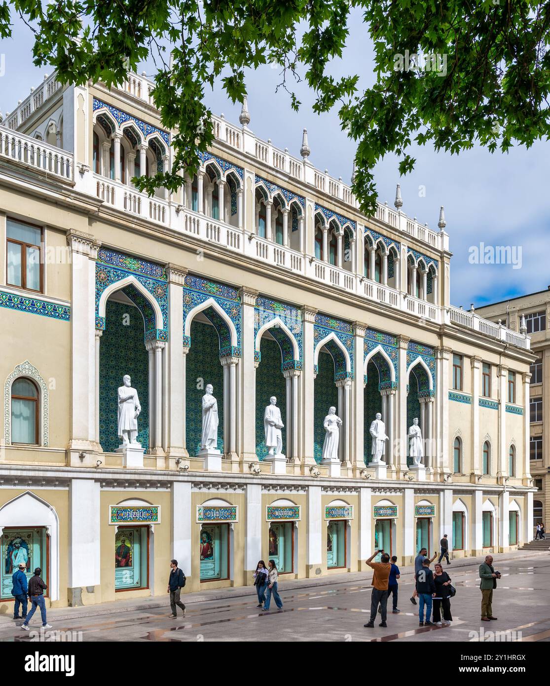Bakou, Azerbaïdjan - 5 mai 2024 : Musée Nizami d'Azerbaïdjan, avec des statues bordant la façade. Le bâtiment est décoré avec des arches et des carreaux complexes. On peut voir des gens marcher près du bâtiment Banque D'Images