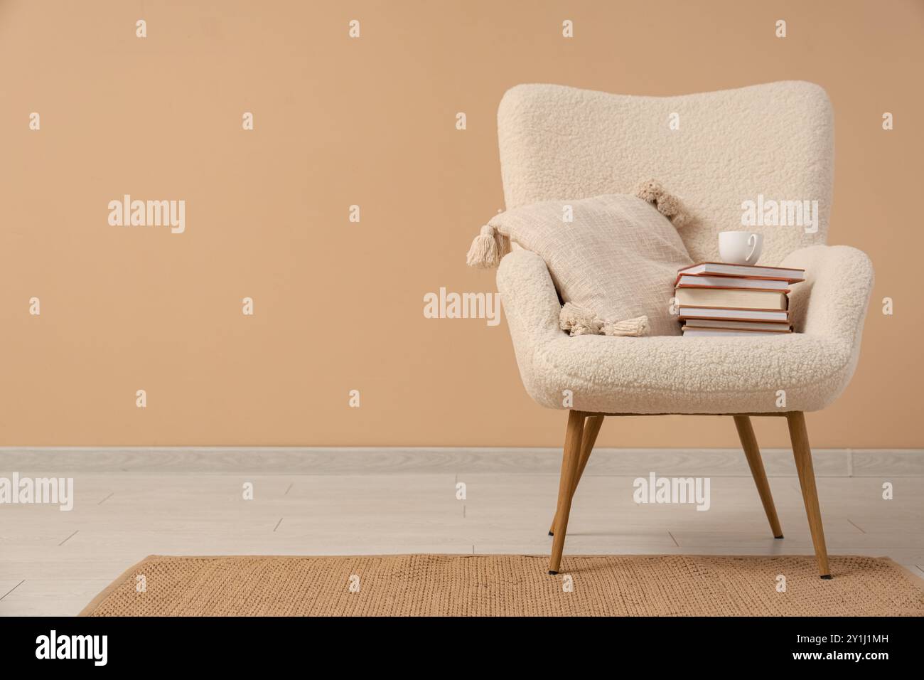 Fauteuil blanc avec pile de livres et thé près du mur beige Banque D'Images