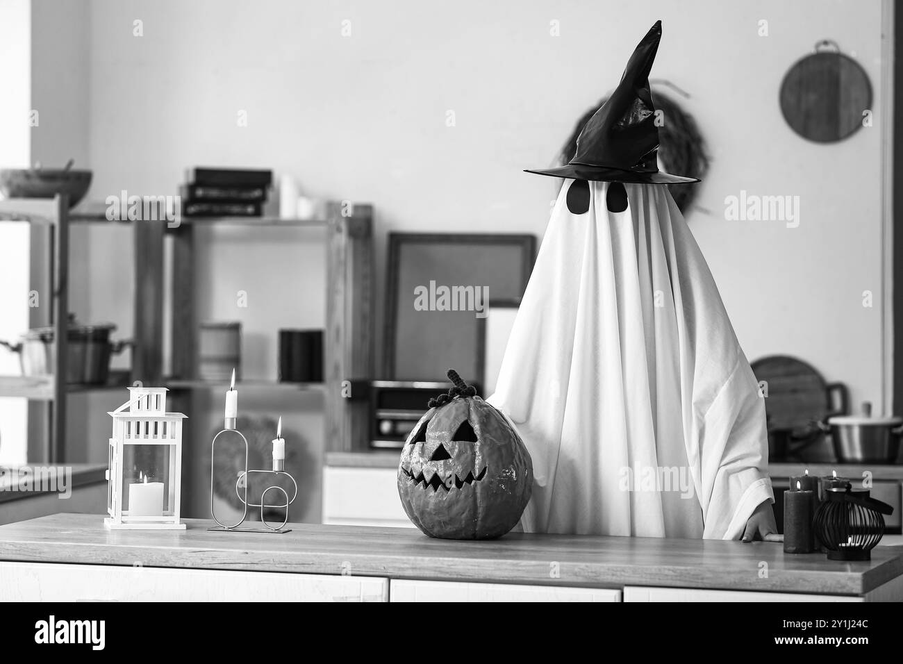 Personne en costume d'Halloween de fantôme avec citrouille sculptée et chapeau de sorcière à la maison Banque D'Images