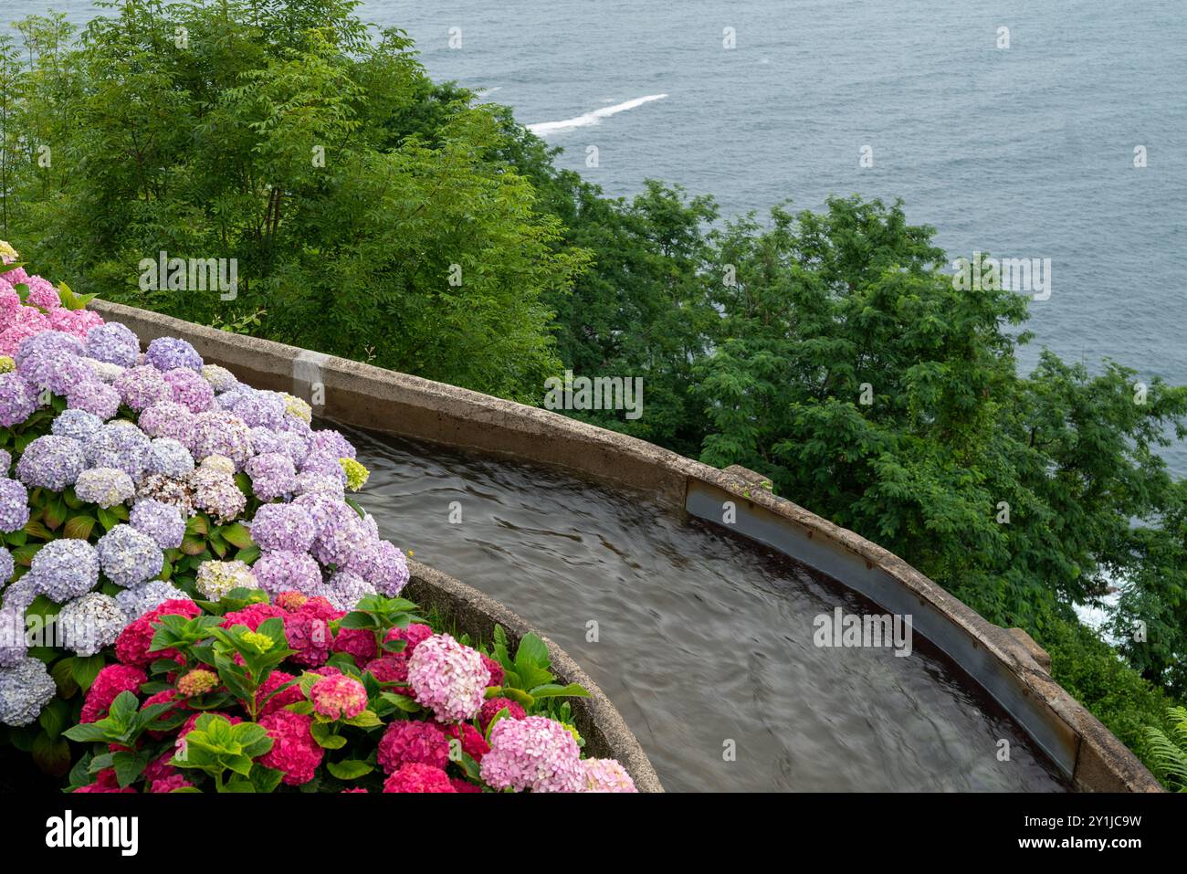 Canal d'eau qui coule, entouré de pétunias et géraniums colorés, en usage dans le parc d'attractions de monte igueldo à Saint-Sébastien en basque Banque D'Images