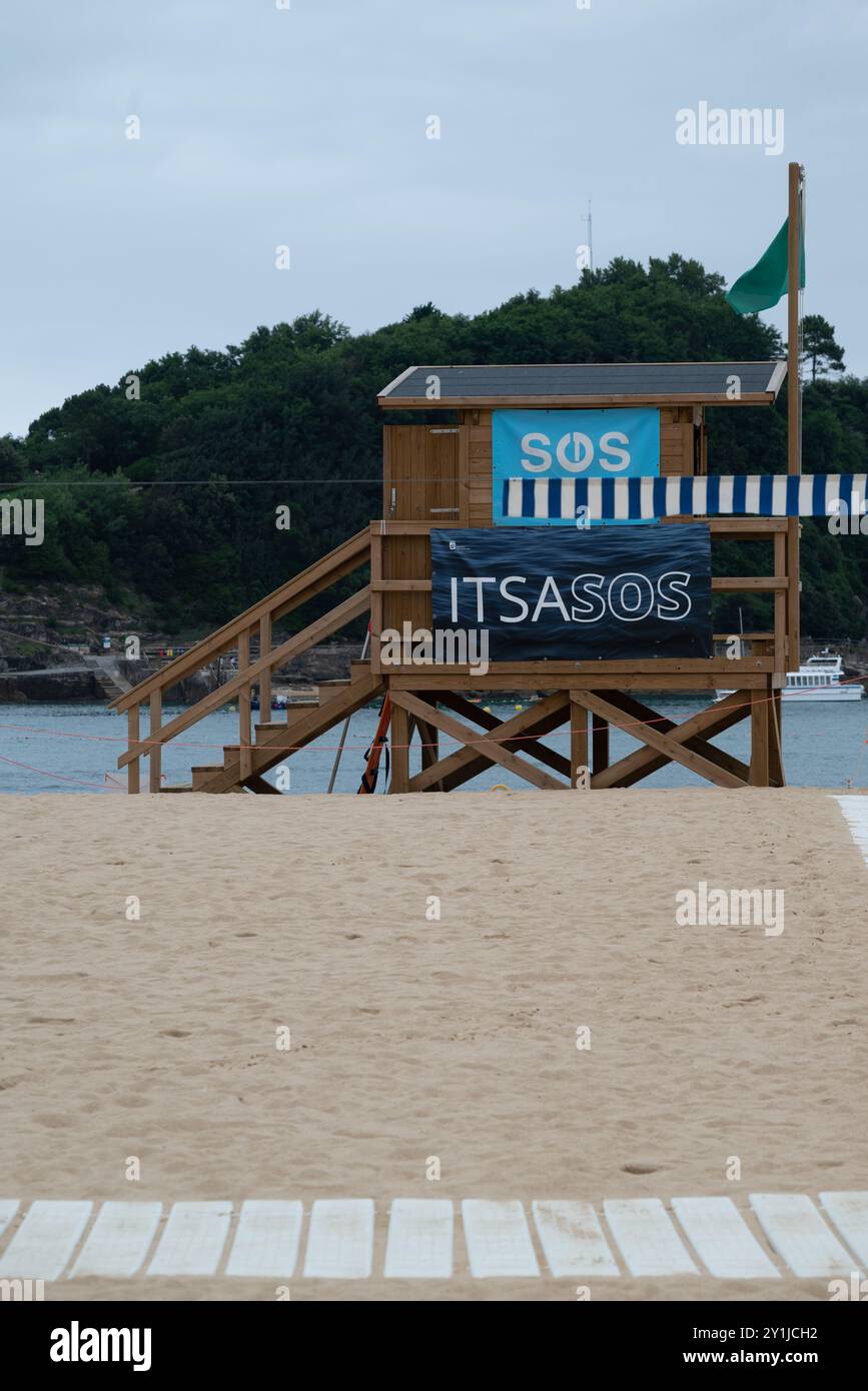 Tour de sauveteur dans la ville de Donostia - Saint-Sébastien dans le nord de l'Espagne, province de Biscaye. C'est un signe SOS. Le jour est venteux, le drapeau vert i. Banque D'Images