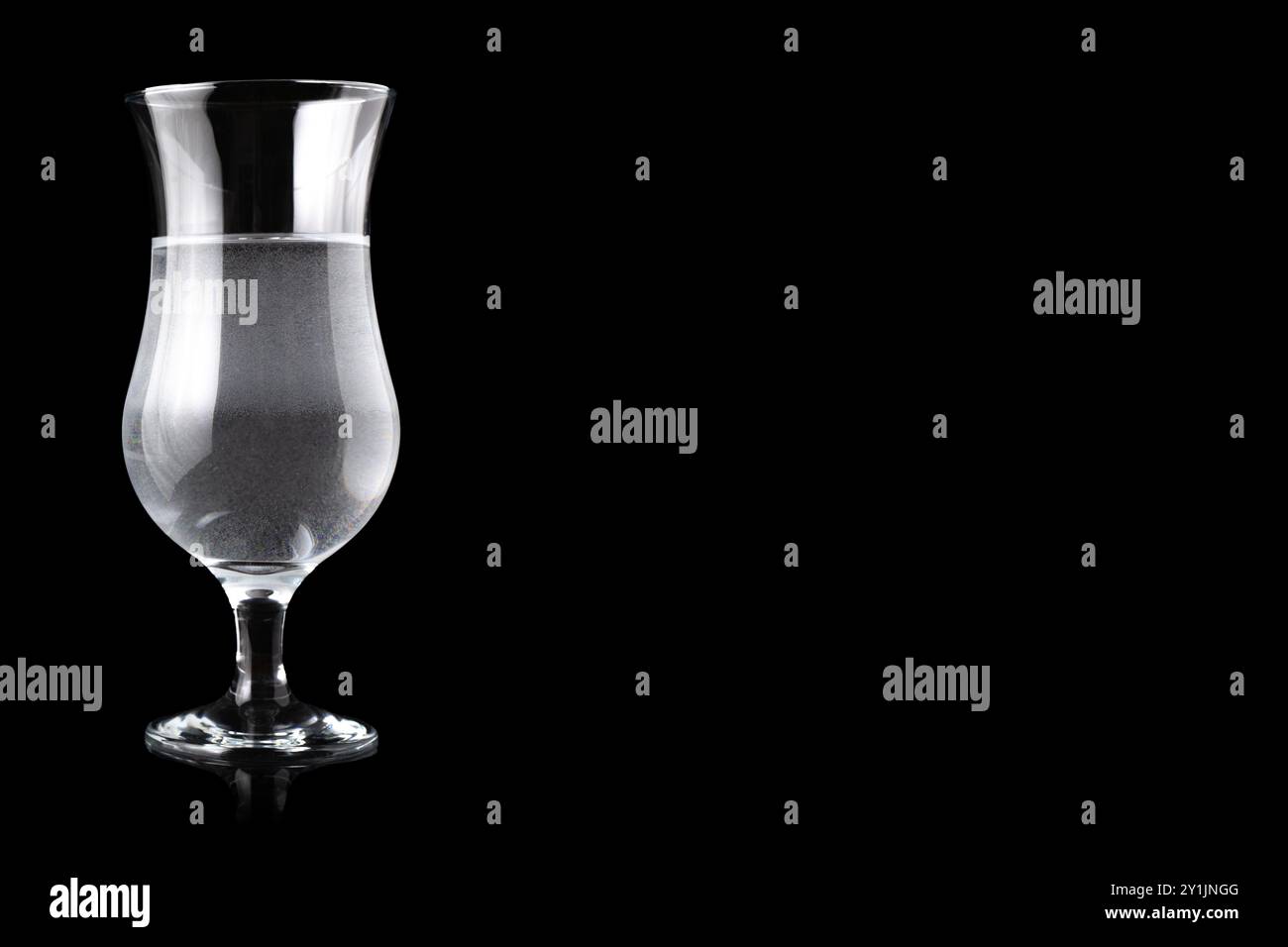 Verre ouragan rempli d'eau, debout sur le côté gauche. Espace vide pour le texte. Banque D'Images