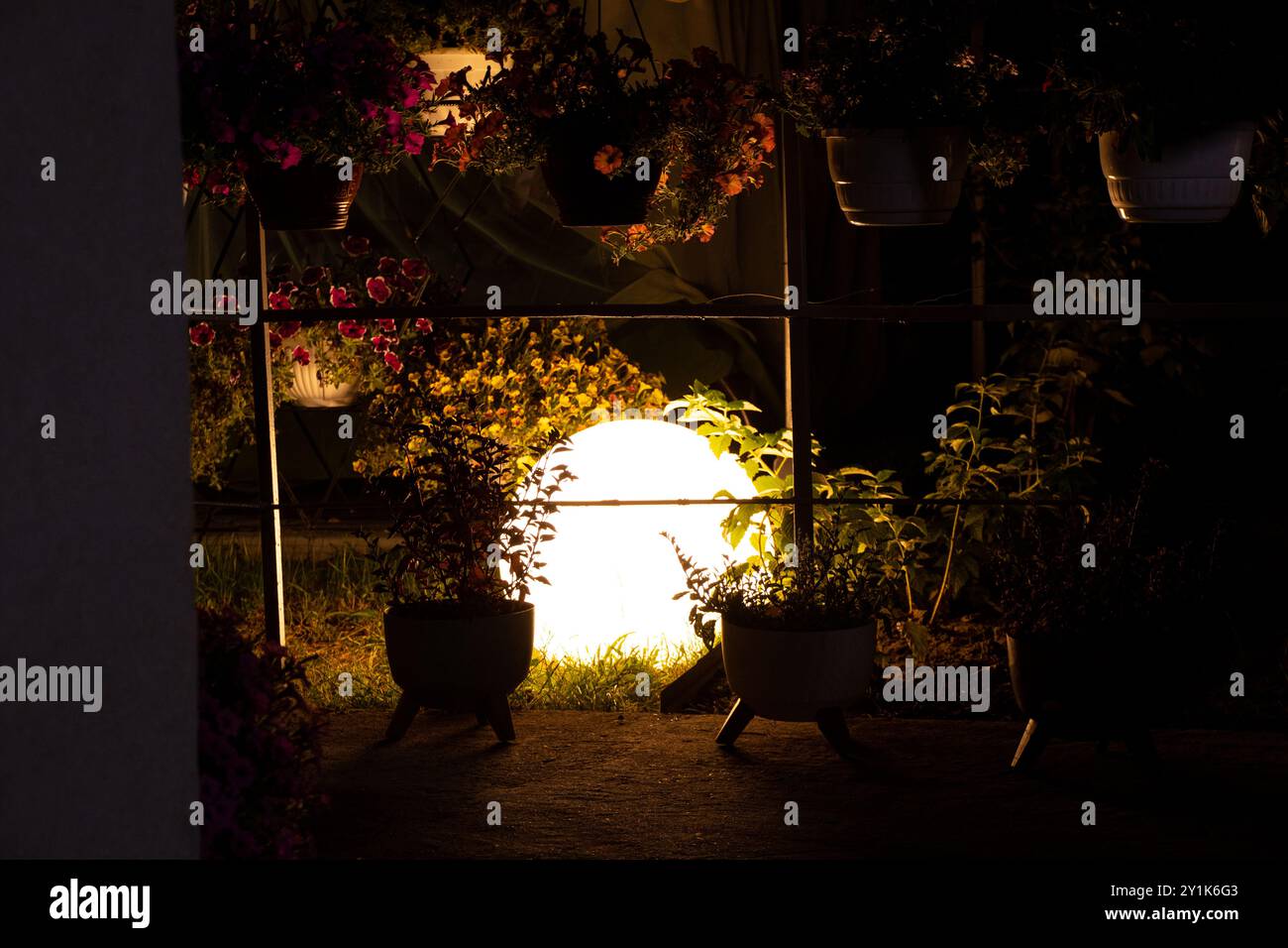 Lampe ronde boule brille la nuit dans le jardin en été dans les fleurs à la datcha, lampe d'éclairage extérieur Banque D'Images