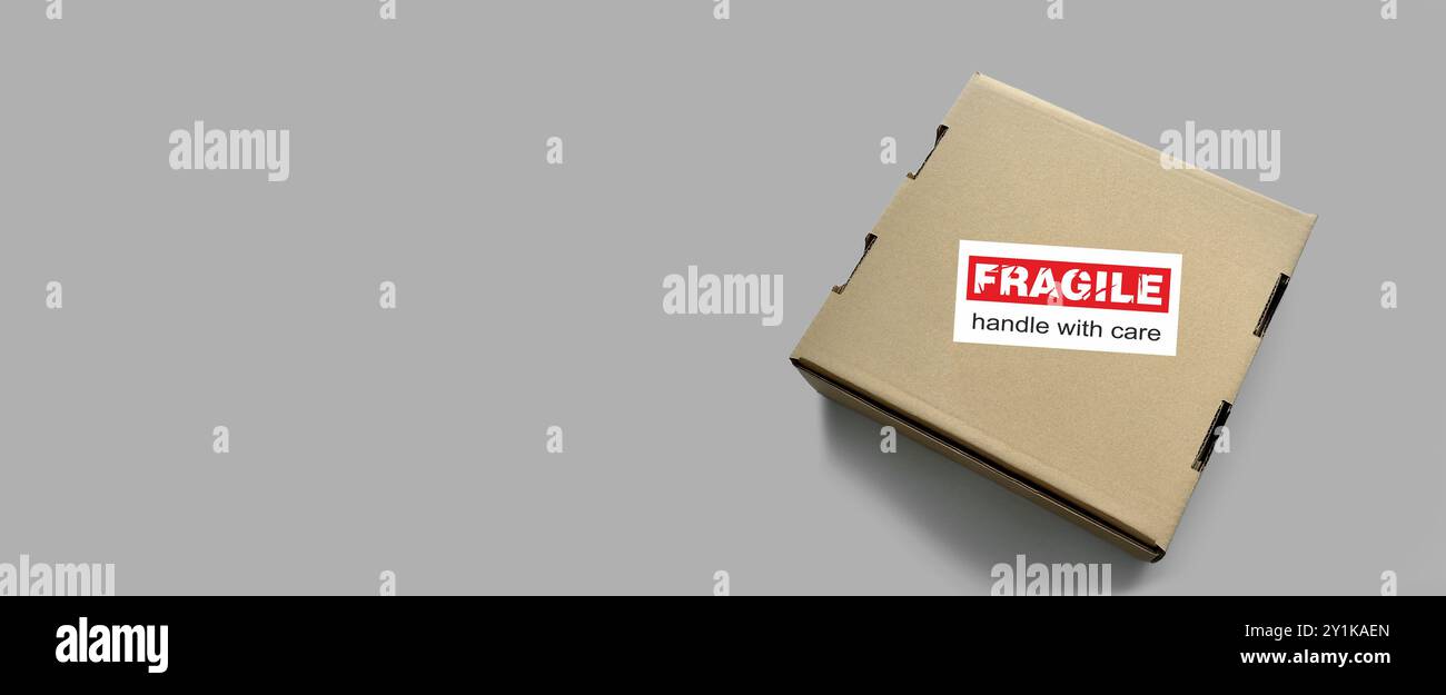 Emballage d'articles fragiles. Boîte d'emballage fermée avec étiquette, autocollant « fragile, manipuler avec précaution ». Rouge, blanc. Emballage, expédition concept d'articles fragiles Banque D'Images