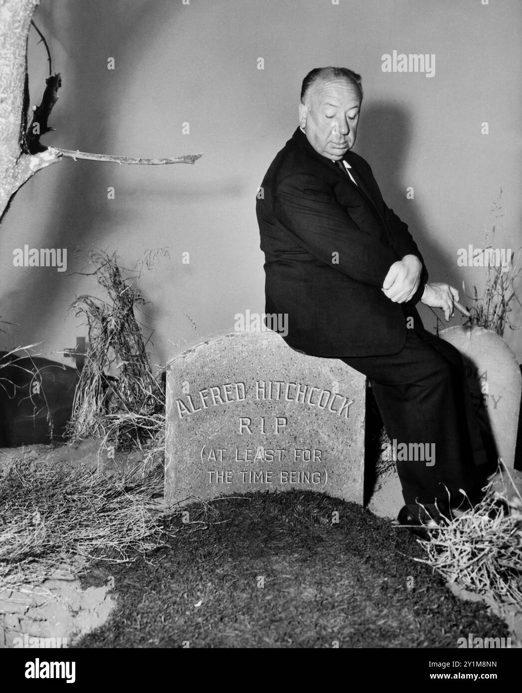 1960 c. , USA : le célèbre réalisateur ALFRED HITCHCOCK ( 1899 – 1980 ), pubblicitaire encore pour la sortie de la publicité de TV série ALFRED HITCHOCH PRÉSENTE ( CBS TV , 1955 - 1962 ). Dans chaque épisode, Hitchcock est apparu au début en tant que présentateur pour introduire l'intrigue de l'épisode, puis réapparaître à la fin en mettant un éclat avec une conclusion 'morale' d'une manière absurde, macabre , drôle et totalement surréaliste comme dans son style. La photo le représente dans l'un de ces moments assis sur une pierre tombale sur laquelle apparaît l'écriture 'ALFRED HITCHCOCK R.I.P. ( AU MOINS POUR LE MOMENT )'. Unkn Banque D'Images