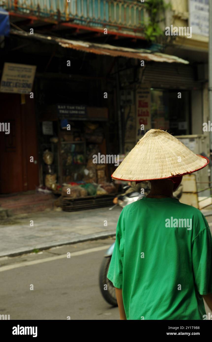 Femmes marchant sous son chapeau asiatique dans la rue Hanoi. Banque D'Images