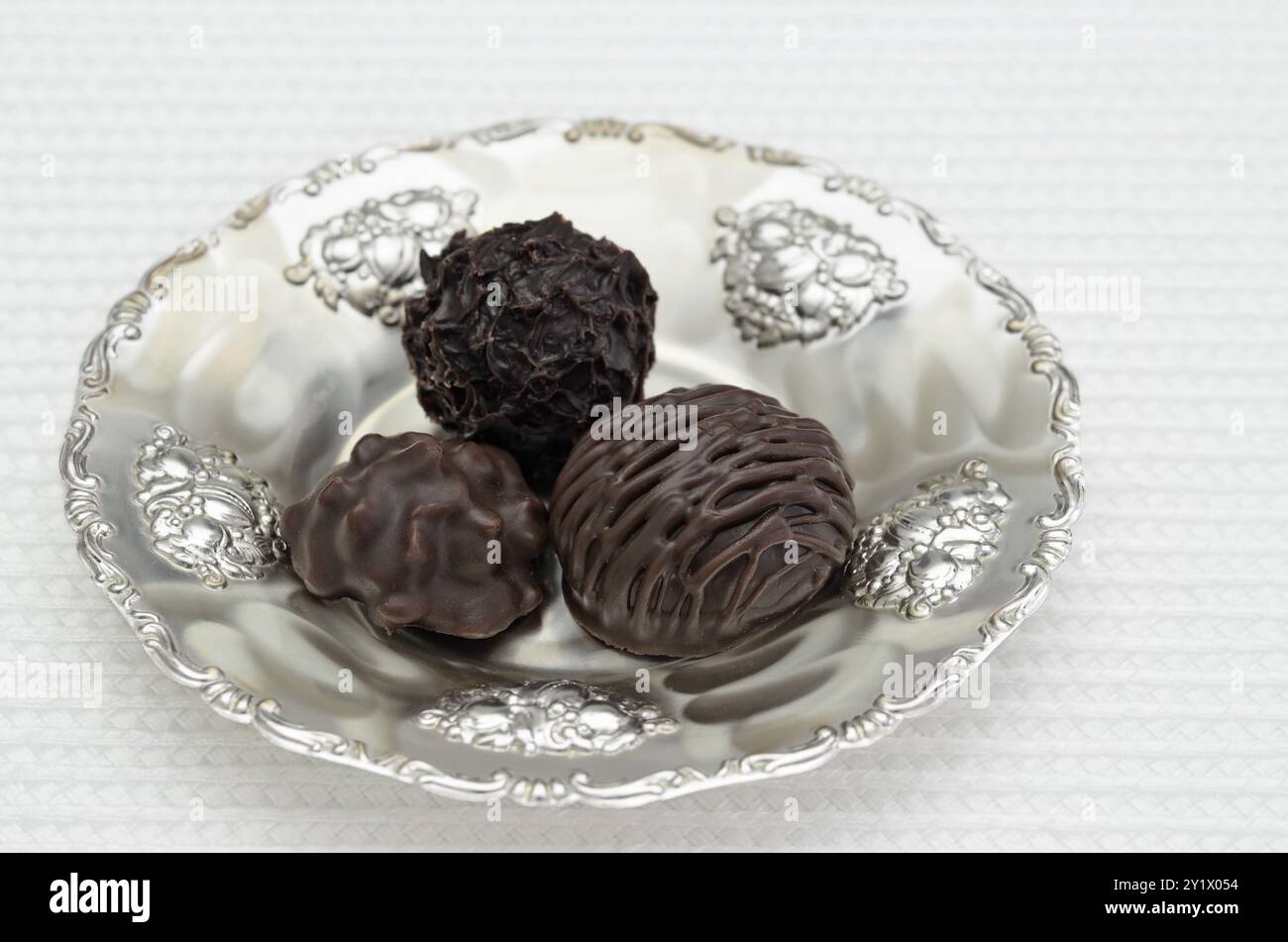 Trois pralines de chocolat sur une plaque d'argent, gros plan, isolés sur fond blanc Banque D'Images