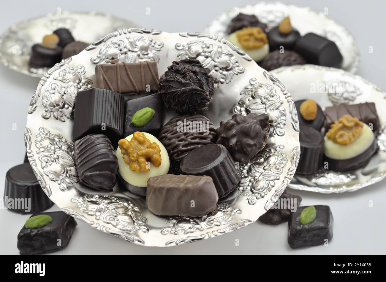 Différents types de pralines au chocolat sur plaques d'argent, gros plan, isolés sur fond blanc Banque D'Images