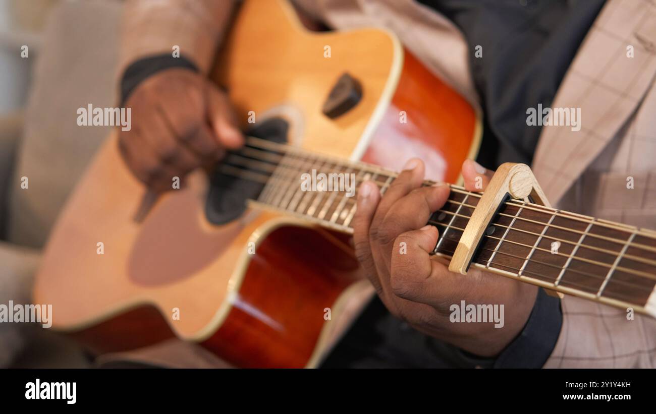 Jouer de la guitare. Performance musicale. Musique blues. Homme talentueux main artiste pratiquant des accords de jazz sur instrument à cordes acoustique avec Capo à l'intérieur. Banque D'Images