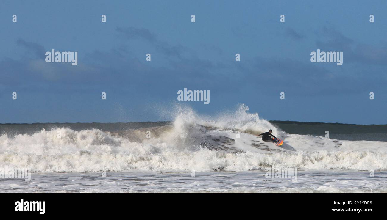 surfeur chevauchant vague dans l'océan sur planche de surf en mer avec bateau et ciel bleu en arrière-plan. Banque D'Images