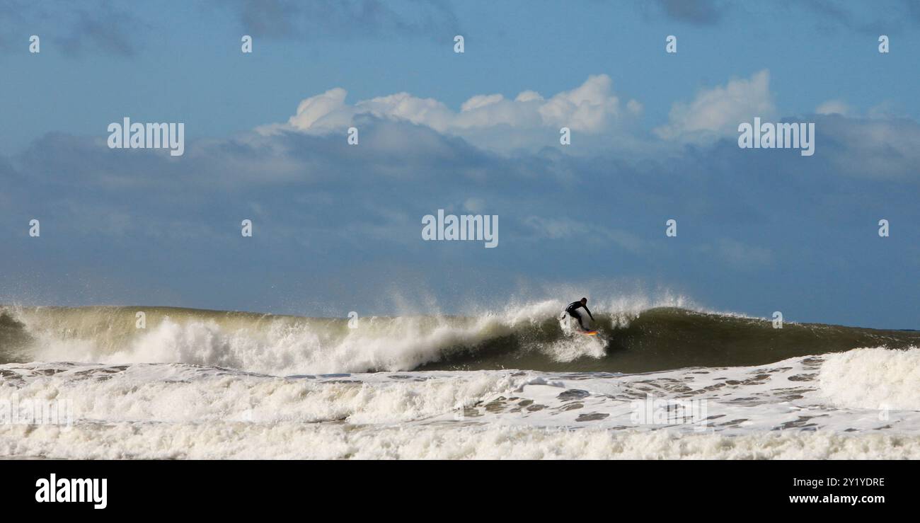 surfeur chevauchant vague dans l'océan sur planche de surf en mer avec bateau et ciel bleu en arrière-plan. Banque D'Images