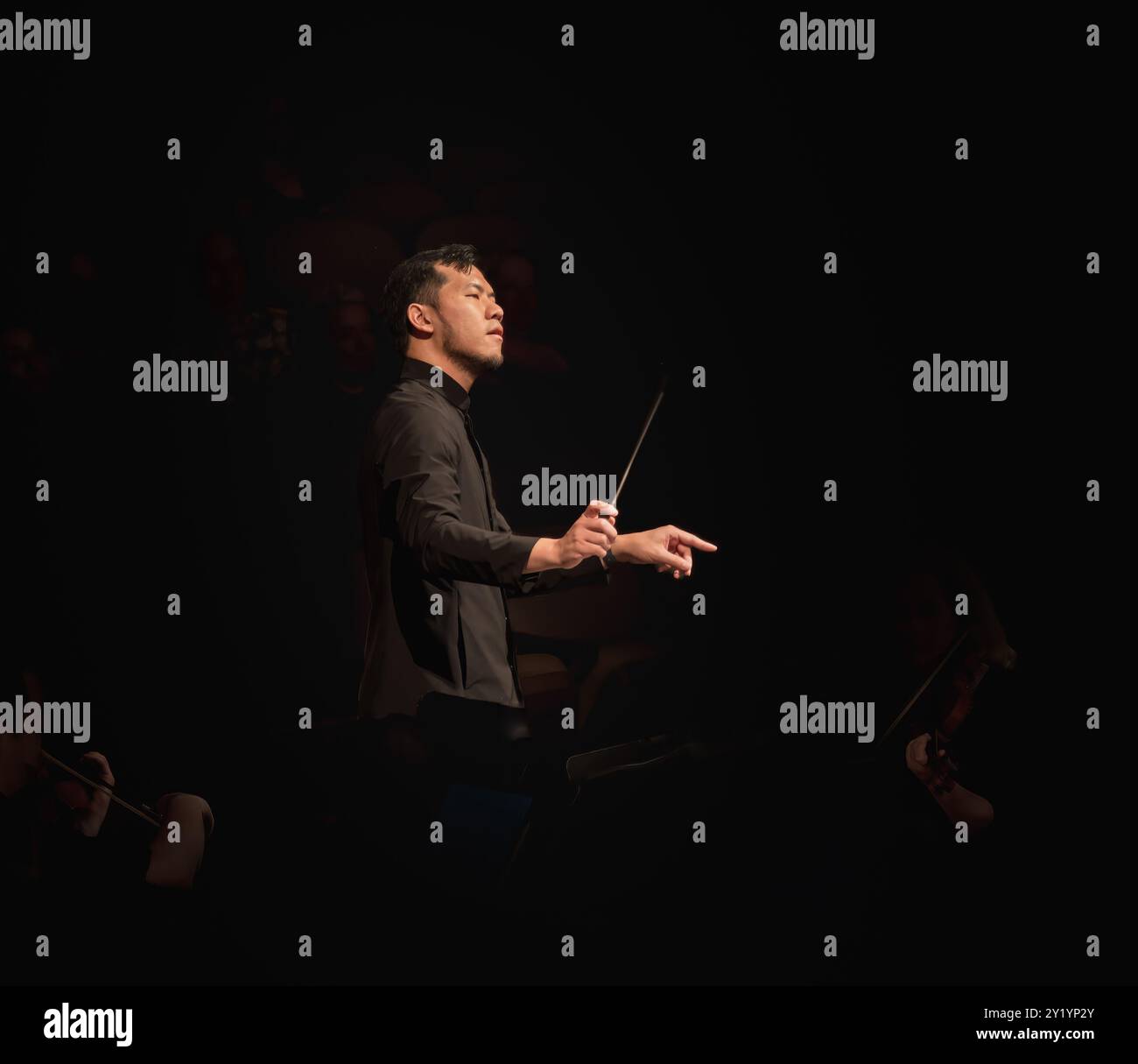 Portrait d'un chef d'orchestre américano-asiatique lors d'une performance d'orchestre symphonique Banque D'Images