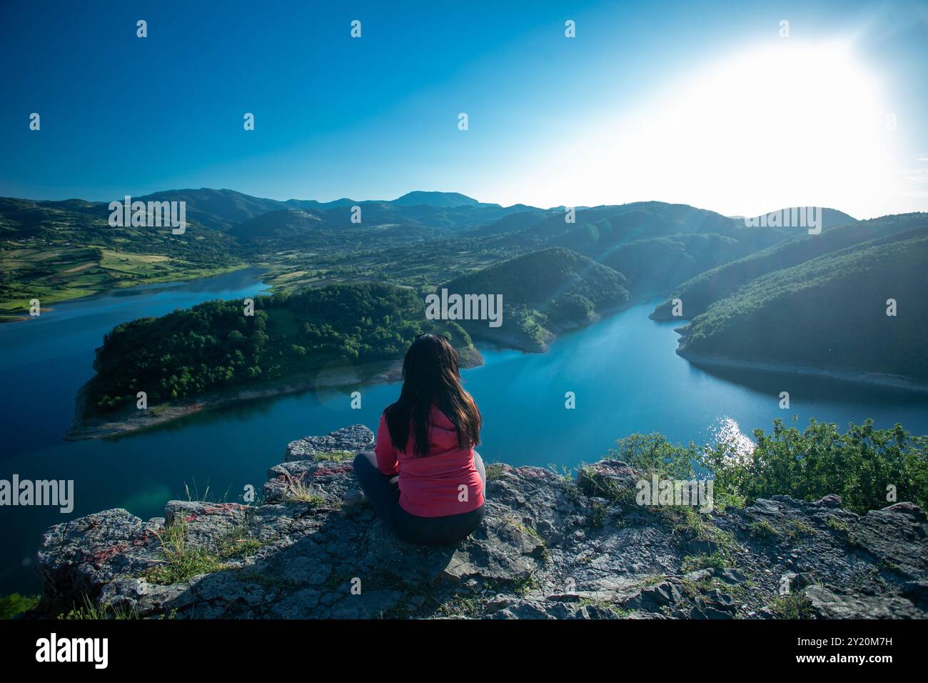 Une femme assise sur Un rocher regardant au-dessus d'Une scène de la nature Beutiful. Une belle vue sur Un lac et les montagnes. Vue rare Banque D'Images