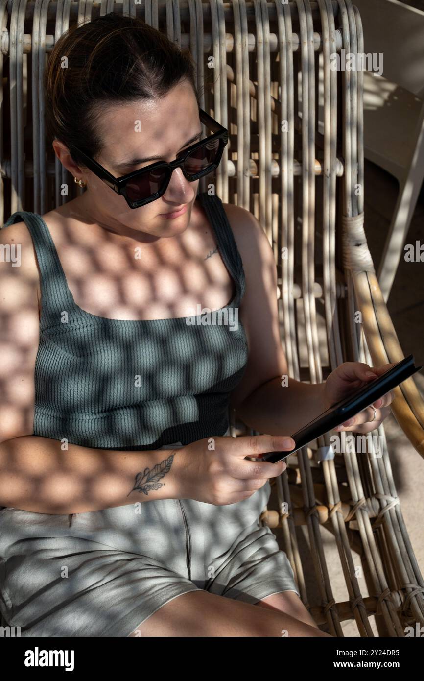 Femme lisant sur une chaise de plage en osier dans les Pouilles, Italie Banque D'Images
