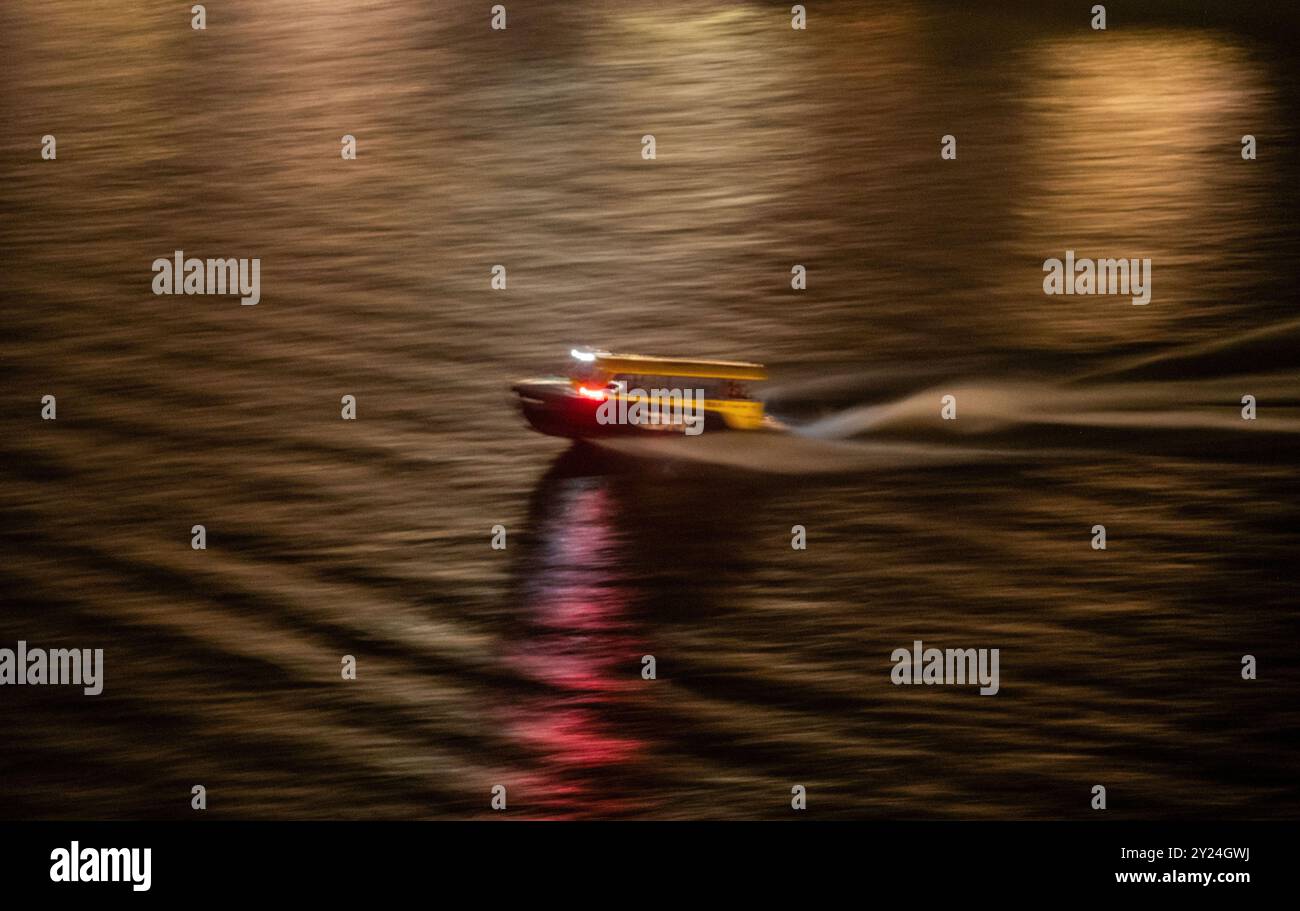 Vitesse de bateau-taxi à travers le port fluvial de la ville la nuit, panoramique flou à grande vitesse Banque D'Images