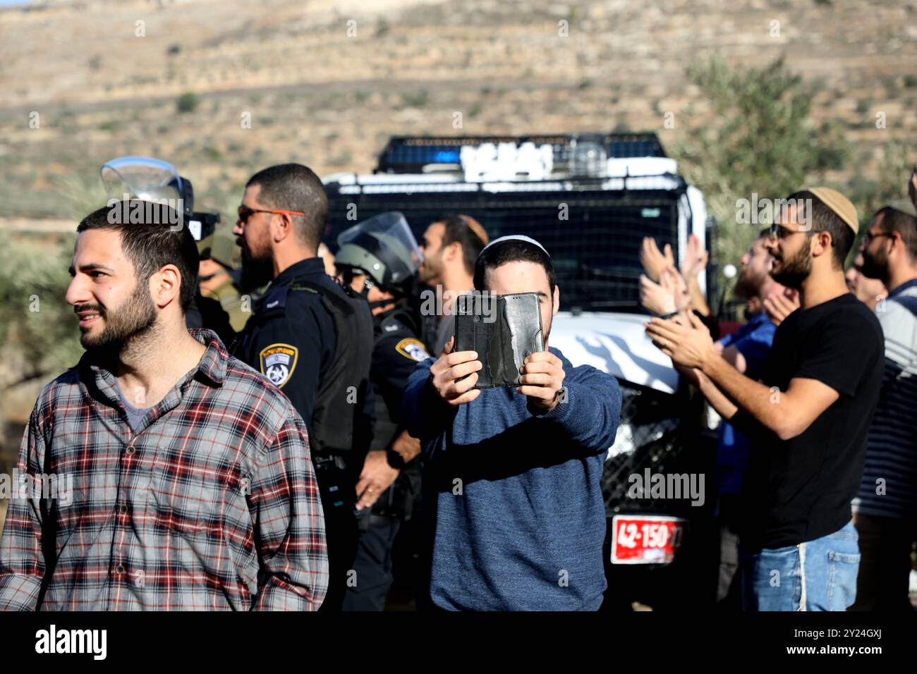 Naplouse, Cisjordanie, Palestine. 28 novembre 2021. Des colons juifs israéliens se rassemblent aux côtés de soldats israéliens dans le village palestinien de Lubban Ash-Sharqiya, au sud de Naplouse. Les colons étaient entrés dans le village alors que certains de ses habitants se rassemblaient pour protester contre les récentes attaques quotidiennes des colons à l’école de Lubban Ash-Sharqiya pour empêcher les élèves d’accéder à l’école et à leurs cours. Les colonies judéo-israéliennes continuent de s'étendre en Cisjordanie et à Jérusalem-est, bien qu'elles constituent une violation du droit international Banque D'Images