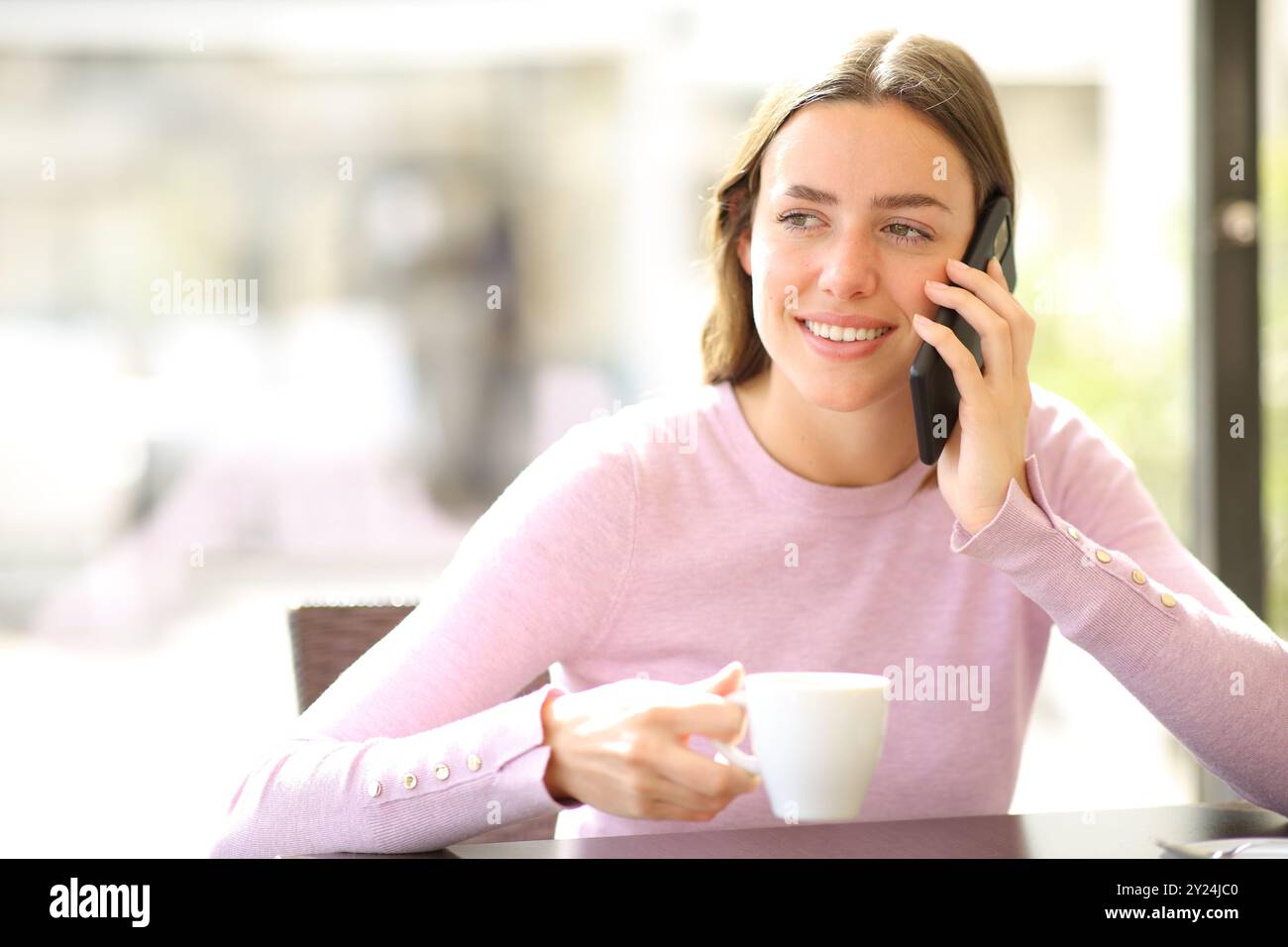 Femme heureuse dans un bar parlant sur téléphone portable buvant du café Banque D'Images