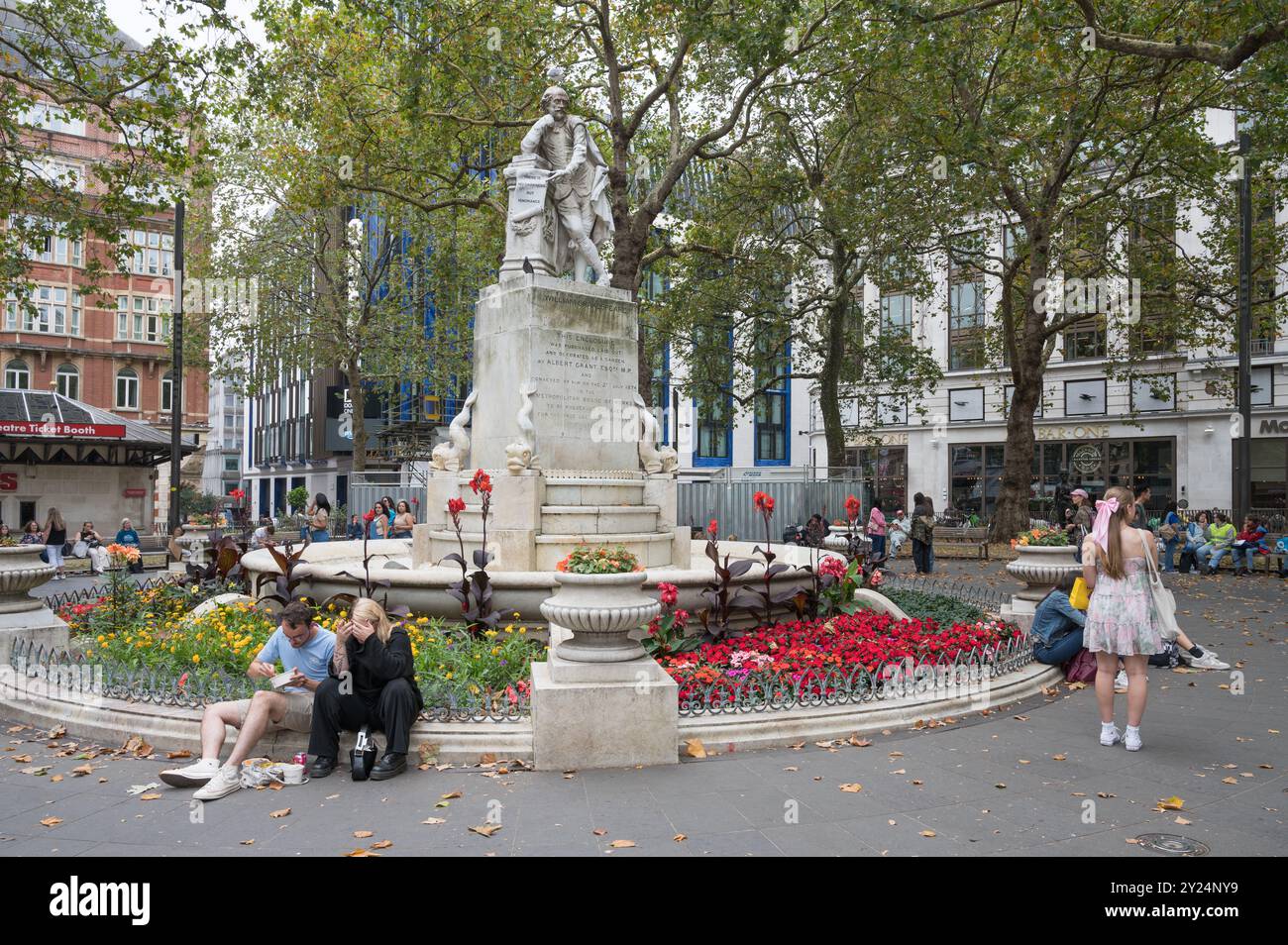 Scène de jour avec des gens autour de la fontaine et statue de Shakespeare dans les jardins de Leicester Square Londres Angleterre Royaume-Uni Banque D'Images