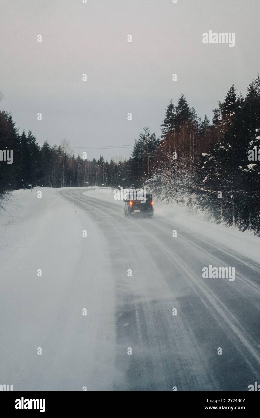 Voiture sur route glacée à travers la forêt arctique enneigée à Ranua, Laponie Banque D'Images