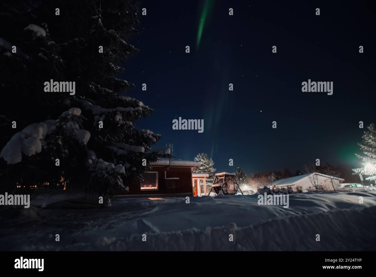 Aurores boréales vertes dans le ciel nocturne au-dessus de la maison et du jardin à Rovaniemi, Laponie Banque D'Images