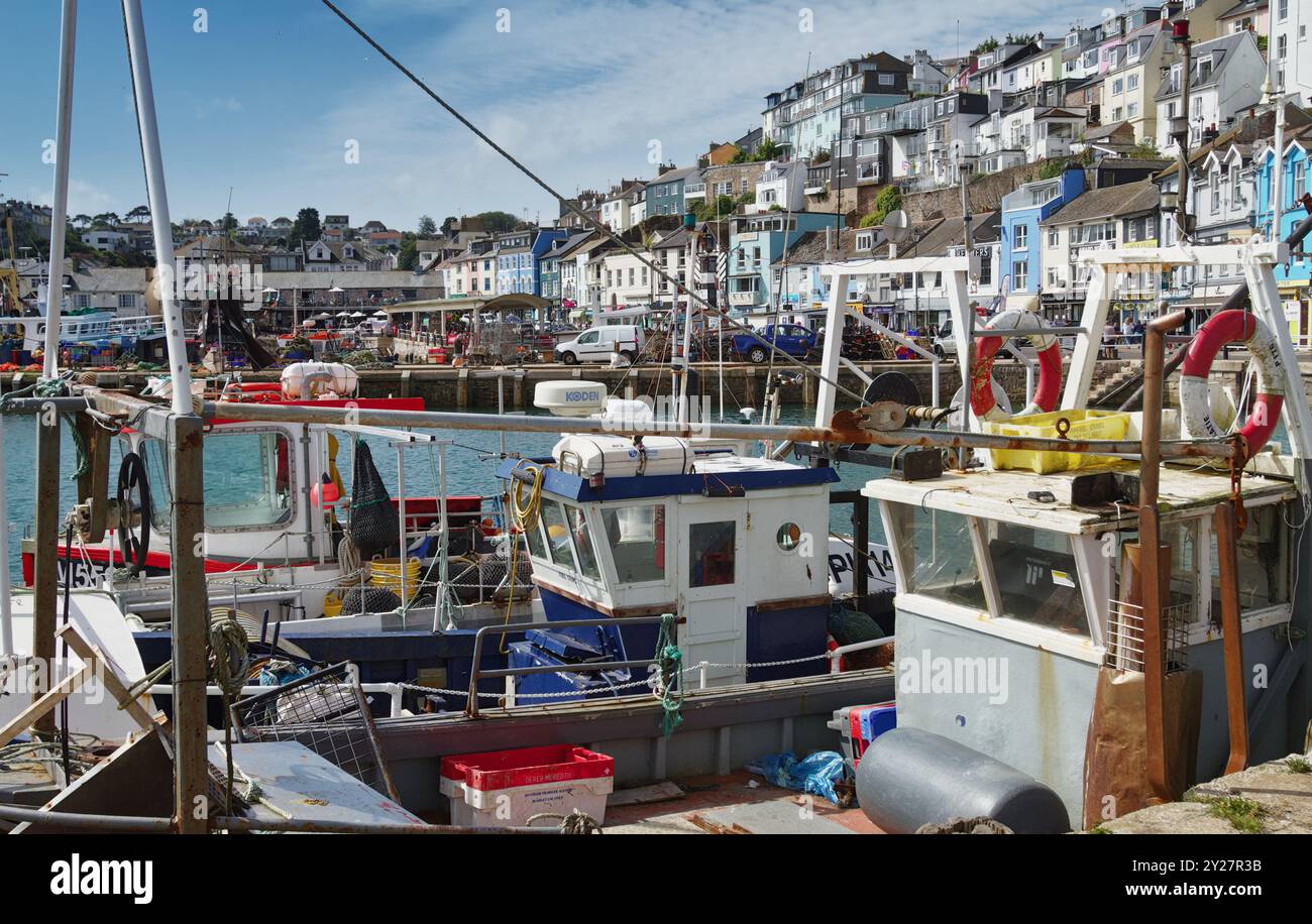 Bateaux de pêche amarrés DANS le port de Brixham avec le quai et les maisons en arrière-plan, Devon UK Banque D'Images
