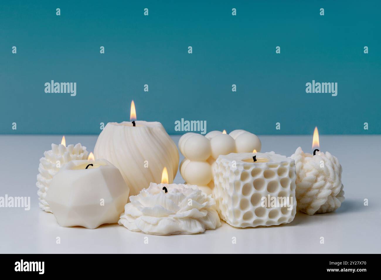 Cirer des bougies faites à la main sur une table blanche sur fond bleu. Bougie parfumée naturelle blanche. Banque D'Images