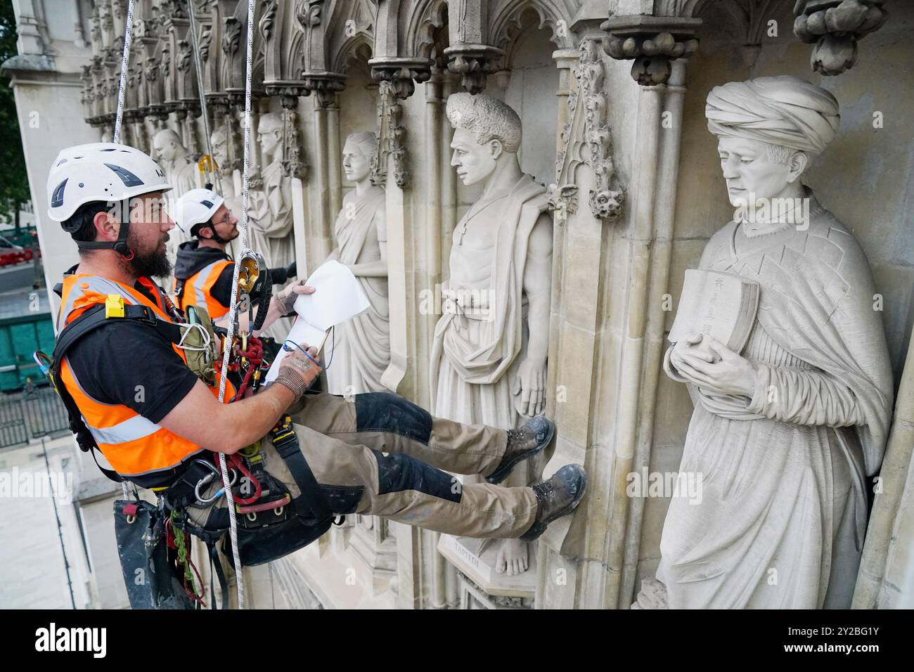 Les spécialistes en rappel Mike Hammond (à droite) et Oscar Banyard (à gauche) réalisent une étude des West Towers de l'abbaye de Westminster, au centre de Londres. L'état de la pierre est vérifié annuellement à l'abbaye. Les West Towers ont été construites entre 1722 et 1745 par Nicholas Hawksmoor et John James, construites à partir de pierre de Portland, à l'un des premiers exemples d'une conception gothique de renouveau. Au-dessus de la Grande porte ouest de l'abbaye se trouvent les dédicaces aux martyrs modernes, dix statues qui commémorent les chrétiens qui ont donné leur vie pour leurs croyances. L'abbaye de Westminster a été le lieu des couronnements de Banque D'Images