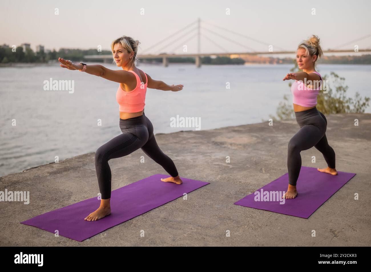 Deux femmes pratiquant le yoga en plein air dans la ville. Virabhadrasana, posture du guerrier 2 Banque D'Images